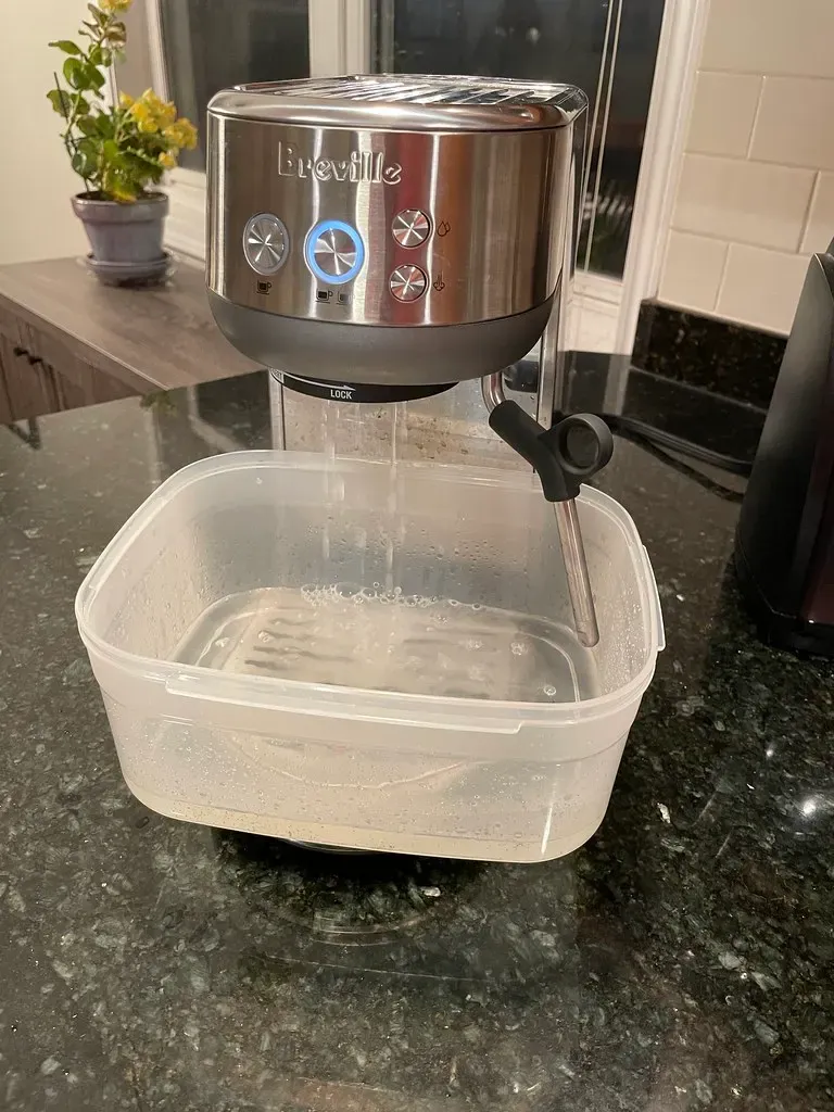 Kaffeemaschine beim Entkalken, die Lösung läuft in eine Schale