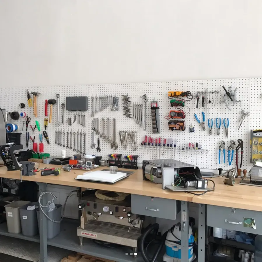 Werkbank mit Lochwand voller Werkzeug, darunter Kaffeemaschinen in Arbeit